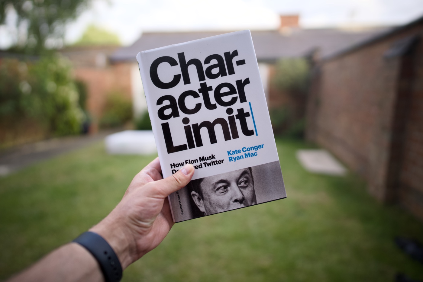 Book &ldquo;Character Limit: How Elon Musk Destroyed Twitter&rdquo; by Kate Conger and Ryan Mac held in a hand on a sunny day