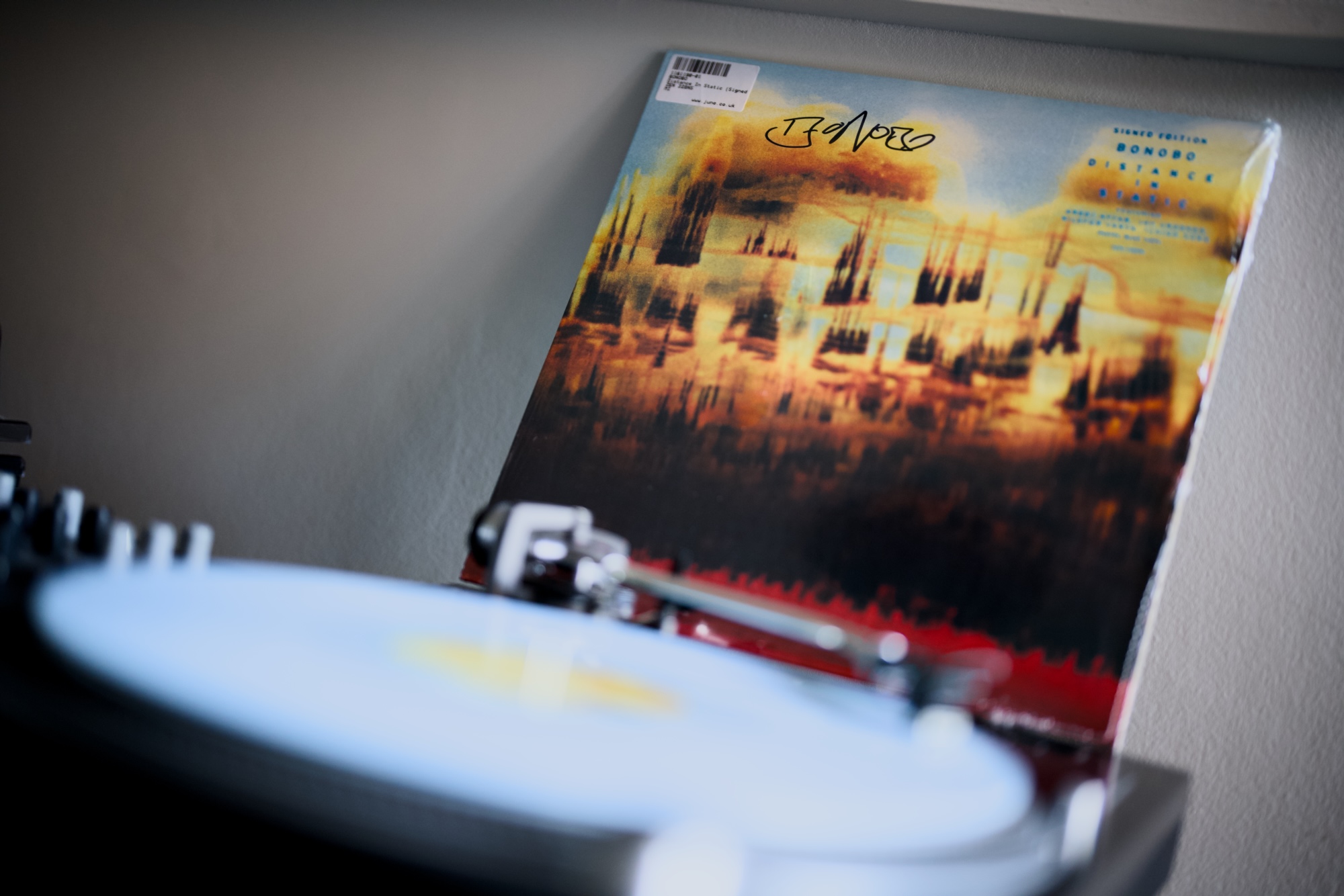 Bonobo “Distance in Static” cover in the bacground in front of a blury record spinning on the turntable